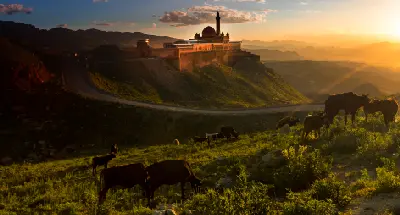 İshak Pasha Palace silhouetted at sunset above grazing cattle near Doğubayazıt, Eastern Turkey.