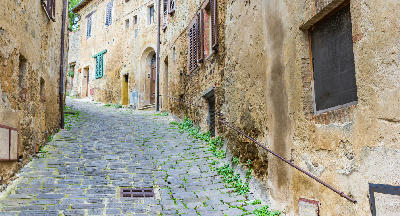Cobblestoned street lined with historic houses in Montalcino, Italy.