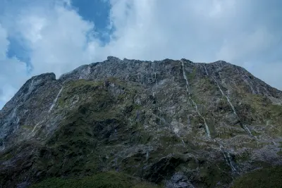 Waterfalls streaming down steep rock cliffs in Cleddau Valley near the Homer Tunnel on the Milford Road in Fiordland National Park, New Zealand.