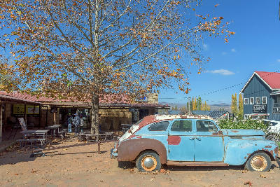 Vintage car parked beside shops and sandstone buildings in the town centre of Clarens, Free State, South Africa.