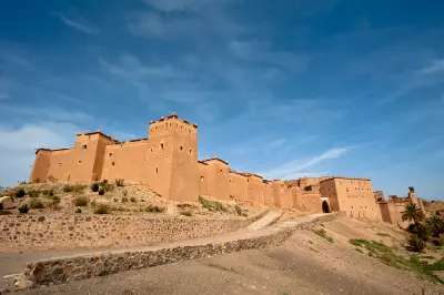 Kasbah Taourirt fortress walls in Ouarzazate, Morocco with arid desert terrain and traditional fortified mud-brick architecture