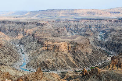 Elevated panoramic view across Fish River Canyon in Namibia showing steep layered canyon walls, plateau formations, and the winding Fish River below.