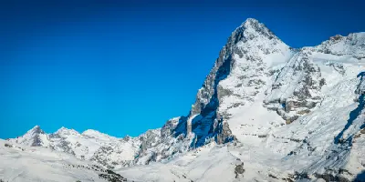Eiger North Face above Kleine Scheidegg with snow-covered slopes and clear blue sky, Bernese Alps, Switzerland.