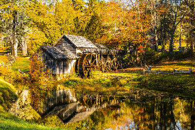Historic Mabry Mill with waterwheel and autumn trees reflected in a pond along the Blue Ridge Parkway in Virginia.