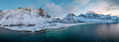Panoramic aerial of Ersfjord Beach showing sandy bay and turquoise water beneath snow-covered mountains