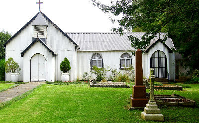 Front view of St John’s Gowrie Church near Nottingham Road in the KwaZulu-Natal Midlands, with historic gravestones and a well-kept churchyard.