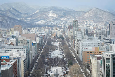 Aerial view of Odori Park in winter with snow festival structures and city buildings in Sapporo, Hokkaido, Japan.