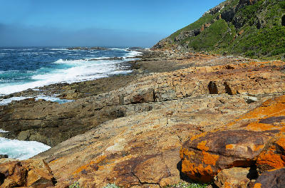 Rocky shoreline and coastal cliffs in Robberg Nature Reserve along the Garden Route of South Africa.