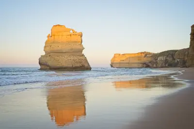 Gog and Magog limestone sea stacks reflected in wet sand at Gibson Steps Beach, Victoria, Australia.