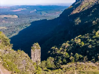 Pinnacle Rock quartzite outcrop overlooking a deep forested gorge and distant lowlands near Graskop, Mpumalanga, South Africa.