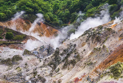 Steam rising from mineral-stained slopes in Jigokudani Hell Valley, Noboribetsu, Hokkaido, Japan.