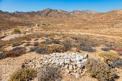 Nama ancestral grave site in the arid Richtersveld landscape with desert mountains and a remote gravel track.
