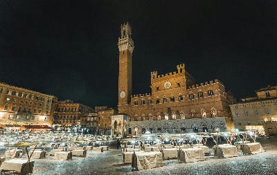 Palazzo Pubblico and Torre del Mangia illuminated at night in Piazza del Campo, Siena, Tuscany, Italy.