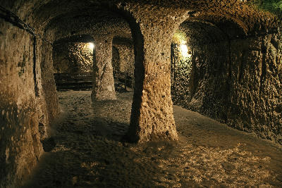 Illuminated rock-cut chambers and arched passageways inside Derinkuyu Underground City in Cappadocia, Turkey.