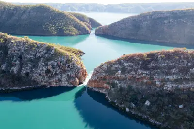 Aerial view of turquoise tidal waters flowing through two narrow gaps in the rugged McLarty Range at Horizontal Falls.