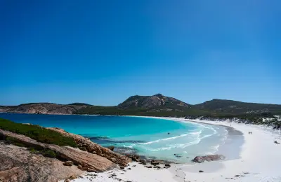 Lucky Bay's white sand and turquoise water framed by granite rocks and coastal hills in Cape Le Grand National Park, Western Australia.