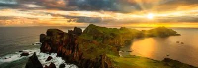 Panoramic sunset view of Ponta de São Lourenço on Madeira Island, showing rugged volcanic cliffs, green ridgelines, and the Atlantic Ocean on both sides.