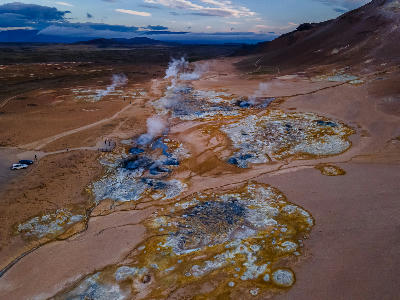 Aerial view of the Námafjall Hverir geothermal area in North Iceland, showing steaming vents, bubbling mud pools, and mineral-stained earth near Lake Mývatn.