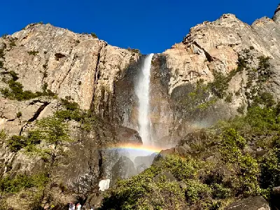 Bridalveil Fall Yosemite with waterfall over granite cliff and rainbow in mist near the base.