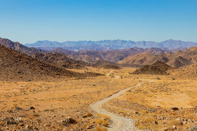 Remote gravel road winding through the arid valleys and mountain ranges of Richtersveld National Park, Northern Cape, South Africa.