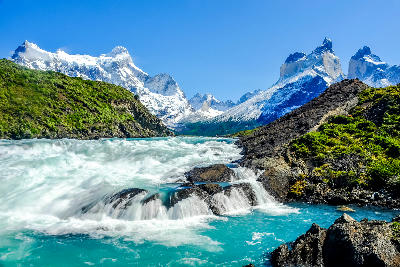Fast-flowing turquoise water at Salto Grande waterfall with the Cuernos del Paine mountains in Patagonia, Chile.