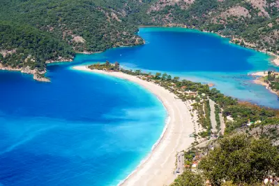 Elevated view of Ölüdeniz Beach and the Blue Lagoon with turquoise water and forested mountains in Türkiye.