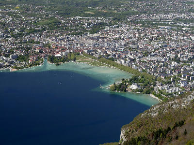 Lake Annecy and Annecy Old Town viewed from Mont Veyrier with deep blue water, curved shoreline, and surrounding urban area