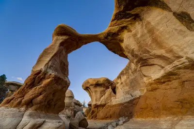 Metate Arch forms a slender natural sandstone span above sculpted orange rock formations in Devil’s Garden.