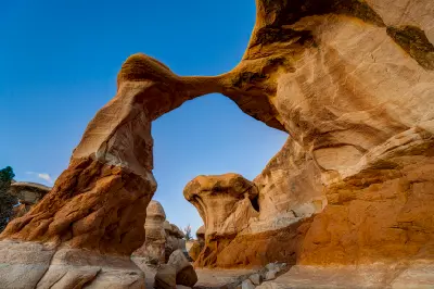 Metate Arch forms a slender natural sandstone span above sculpted orange rock formations in Devil’s Garden.