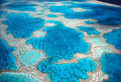 Aerial view of coral formations and blue lagoons across the Great Barrier Reef, Queensland, Australia.