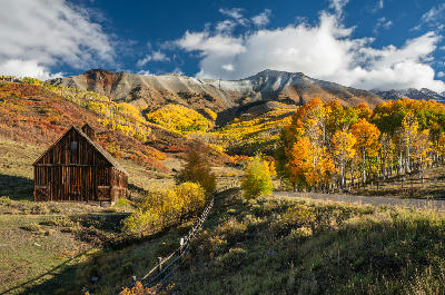 Autumn aspens and old barn on Last Dollar Road with San Juan Mountains near Telluride, Colorado.