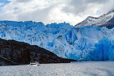 Grey Glacier with blue ice wall and boat on Lago Grey in Patagonia Chile.