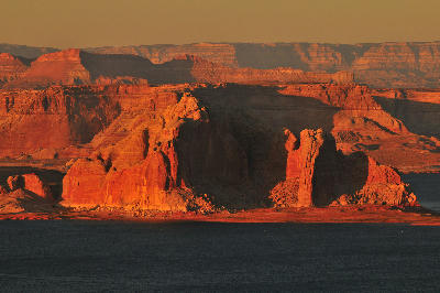 Sunset view from Wahweap Overlook near Page, Arizona, showing Lake Powell with illuminated sandstone buttes and cliffs above the water.