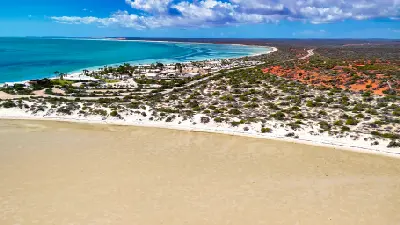 Aerial view of Monkey Mia with turquoise water, white beaches and the coastal settlement beside Shark Bay.