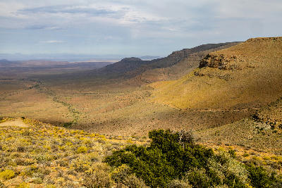 View from Gannaga Pass across the vast Tankwa Karoo, with layered escarpments, desert plains and winding gravel roads stretching into the distance.