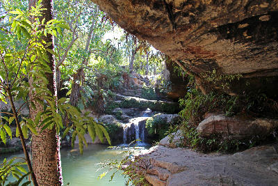 Hidden waterfall and emerald swimming pool beneath sandstone overhangs in Isalo National Park, Madagascar