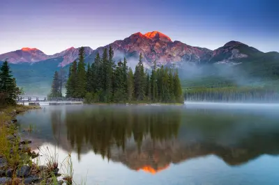Pyramid Lake at sunrise with mist, forested island, and mountain peaks glowing in early light