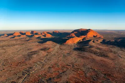 Aerial view of the sandstone domes of Kata Tjuta glowing in evening light across the desert of Northern Territory, Australia.