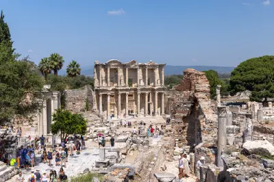 Wide view of the Library of Celsus and surrounding ruins in ancient Ephesus, with visitors walking along the marble street.