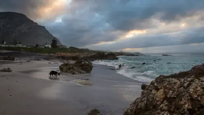 Moody coastal shoreline at Voëlklip Beach in Hermanus with rocky coves, surf, and storm clouds over Walker Bay