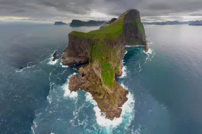 Aerial view of Kallur Lighthouse headland on Kalsoy in the Faroe Islands with steep cliffs above the Atlantic Ocean.