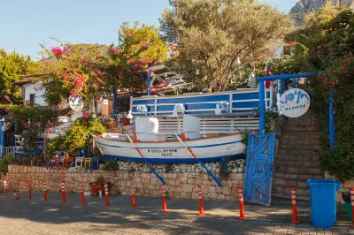 Traditional blue-and-white meyhane in Kaş decorated with a wooden boat and bright bougainvillea.