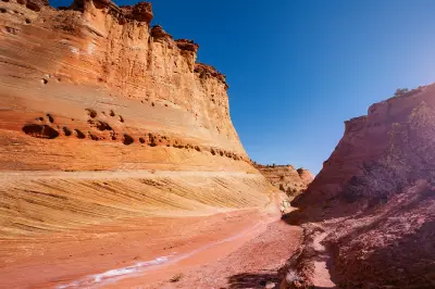 Layered sandstone canyon walls and a dry sandy wash on the approach to Zebra Slot Canyon in southern Utah.
