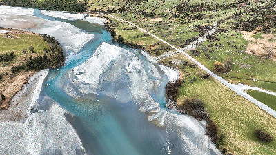 Aerial view of turquoise channels of the braided Dart River flowing through farmland near Glenorchy, South Island, New Zealand.