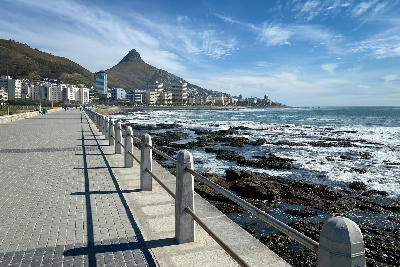 Sea Point Promenade with Lion’s Head rising behind the Sea Point coastline in Cape Town, South Africa.