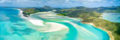 Aerial panorama of white silica sandbanks and turquoise tidal channels at Hill Inlet beside Whitehaven Beach, Queensland.