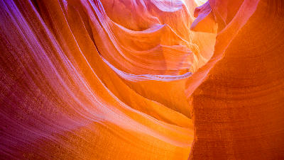 Lower Antelope Canyon in Arizona showing smooth curved red and orange sandstone walls with narrow slot canyon formations and reflected light.