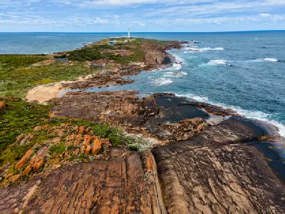Elevated view across the rocky Cape Leeuwin coastline toward Cape Leeuwin Lighthouse near Augusta, Western Australia.