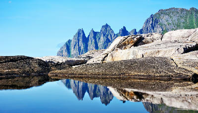 Okshornan peaks reflected in still tidal pools along the Senja coastline