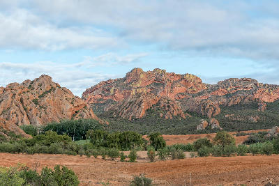 Dramatic red sandstone cliffs and rocky ridges at Red Stone Hills overlooking Klein Karoo farmland and vegetation near Oudtshoorn in the Western Cape, South Africa.